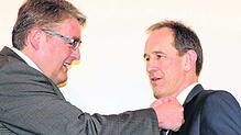 Bürgermeister Bernd Gombold (links) steckt Walter Grom die Ehrennadel des Landes Baden-Württemberg an.