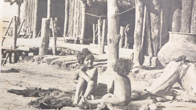 Maria Bußmann vor den ersten beiden Pfahlbauhäusern von 1922, den Riedschachen-Häusern. Sie sitzt fast an derselben Stelle wie vor 95 ...