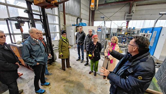 Interessiert lauschen die Besuchern den Worten von Robert Schmid. In der Produktionshalle werden Steinplatten geschliffen.