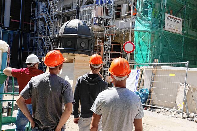 Interessiert verfolgten die Kollegen auf der Baustelle das Tun beim Aufziehen der Turmspitze.