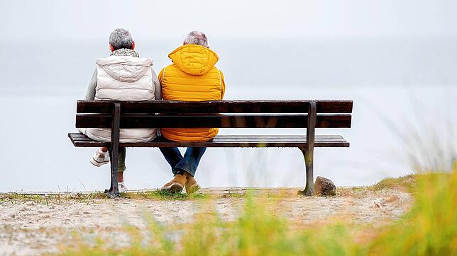 Zwei ältere Menschen sitzen bei trübem Wetter auf einer Bank. Die Aussichten für das Alter sind in anderen Ländern besser.
