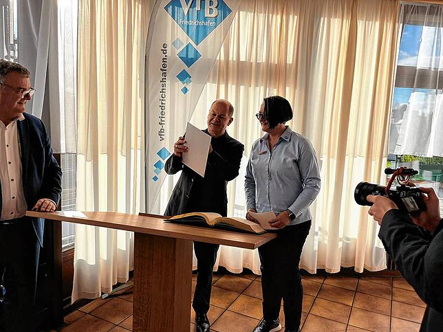 Kanzler Olaf Scholz trägt sich ins Goldene Buch der Stadt ein.