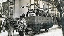 Mit Geldscheinen behangener Narr, im Hintergrund der Themenwagen zur Börse und der Hyperinflation: Villingen 1924.