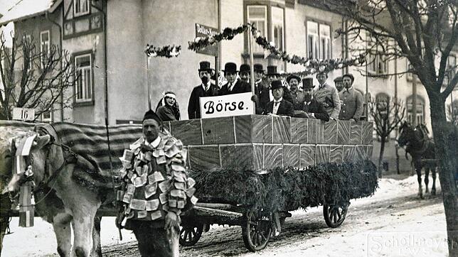 Mit Geldscheinen behangener Narr, im Hintergrund der Themenwagen zur Börse und der Hyperinflation: Villingen 1924.