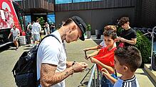 Nationalspieler David Raum steigt als erster aus dem Bus und gibt ein paar jungen Fußballfans Autogramme.