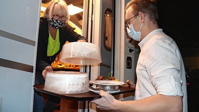 Sternen-Mitarbeiter Hakon Krenz bringt Irene Wisko und ihrem Mann die Gänsekeule von der Küche ans Wohnmobil.
