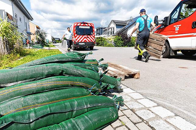 Mitglieder der Feuerwehr legen Paletten aus, auf die die Anwohner ihre nicht mehr benötigten Sandsäcke deponieren können.