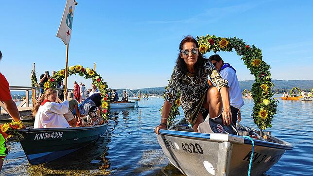Mit Fahne, Blumenkranz und Passagieren kommt es über den Zeller See aus Moos gefahren: Ein Boot der Wasserprozession vor dem Anlanden in ...