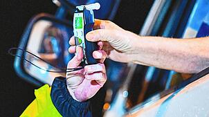 (Symbolbild) Ein Polizist reicht einem Fahrer ein Alkoholmessgerät. Auch in Singen ertappten Beamte am Fasnachtssamstag zwei Alkoholsünder.