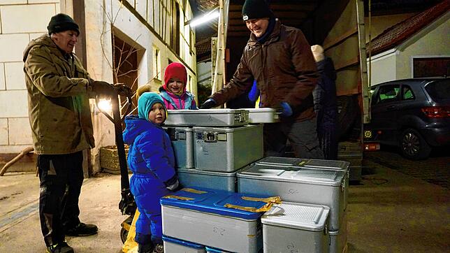 Am späten Freitagabend werden die Hilfsgüter verladen. Der dreijährige Jonas und seine Schwester helfen kräftig mit.