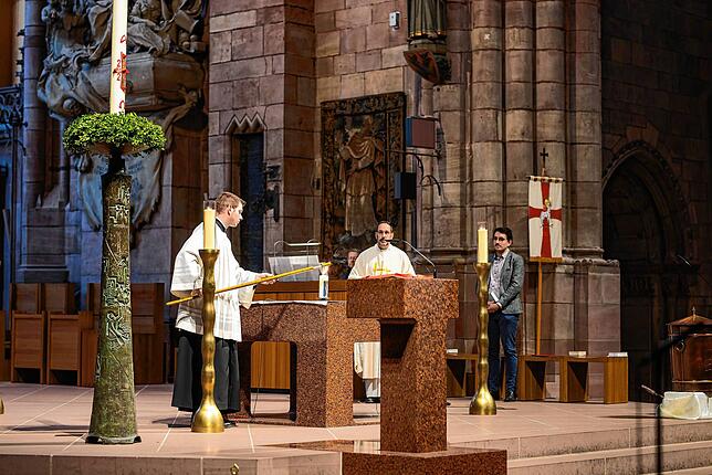 Ein Freiburger Münstermesner entzündet während einer Eucharistiefeier eine Kerze für den verstorbenen Papst Franziskus.