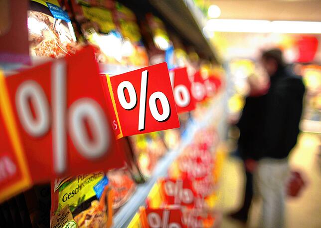 Prozentzeichen hängen in einem Supermarkt an Regalen – Kunden bezahlen Rabatte oft mit ihren Daten.