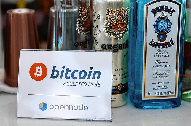 Ein Schild zeigt an, dass hier die Bezahlung mit Bitcoins akzeptiert ist. Die Kryptowährung wird weitgehend noch im Internet als ...
