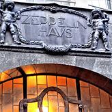 „Zeppelin-Haus“ – eingefasst in Jugendstil-Ornamentik. Darunter das Fenster mit Girlande über dem Haupteingang des ...
