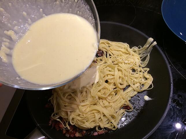 Die Sahne-Ei-Käse-Mischung wird in der Pfanne über die Spaghetti gegeben.