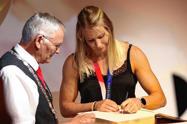 Tribergs Bürgermeister Gallus Strobel verfolgt, wie sich Aline Rotter-Focken im goldenen Buch seiner Stadt verewigt.