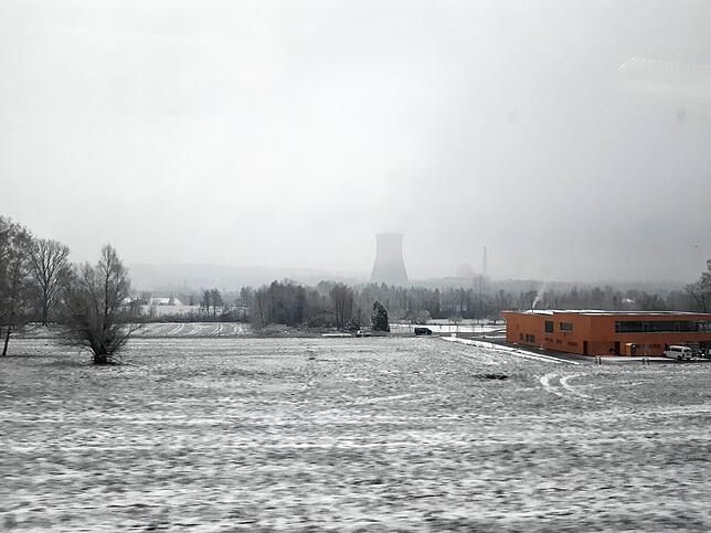 Schnee liegt auf einer Wiese bei Dogern. Im Hintergrund ist das KKL Leibstadt zu sehen, im Vordergrund der Neubau des Feuerwehrgerätehaus.