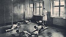 Fünf Buben kriechen nach Trommelschlag einer Betreuerin über den Boden in einem Kinderkurheim. Heute sind viele ehemalige Kurkinder an ...