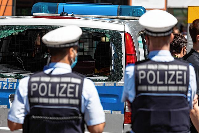 Am Tag danach in Stuttgart: Polizeibeamte vor einem demolierten Einsatzfahrzeug.