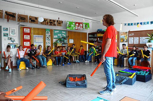 Mit orangenen und gelben Boomwhakers klopfen die Jungen und Mädchen den Rhythmus, den Erlebnispädagoge Uwe Pfauch ihnen vorgibt.