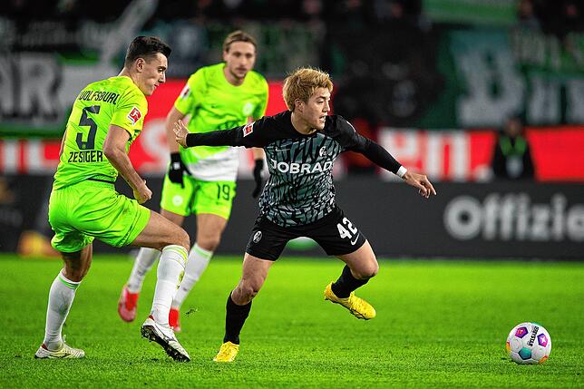 Freiburgs Ritsu Doan (r) spielt gegen Wolfsburgs Cedric Zesiger.