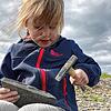 Die fünfjährige Henriette bearbeitet ein Stück Schiefer mit dem Hammer auf der Suche nach Fossilien.