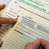Ein Mann füllt den Vordruck für eine Einkommensteuererklärung aus. Nach der Abgabe der Erklärung musste er auf den Steuerbescheid des ...