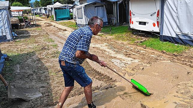 Dietmar Heuter versucht mit einer Schneeschaufel das Vorzelt seines Campingwagens vom schweren Schlamm zu befreien.