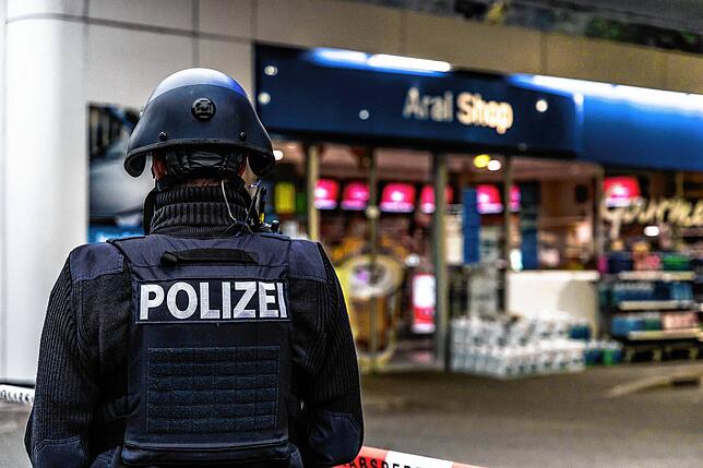 Ein Polizist sichert am frühen Morgen eine Tankstelle in Idar-Oberstein, weil ein Angestellter von einem mit einer Pistole bewaffneten ...