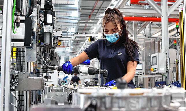 Eine ZF-Mitarbeiterin verschraubt in einer Montagehalle für Elektromobilität der ZF Friedrichshafen AG in Schweinfurt ein Bauteil. ...