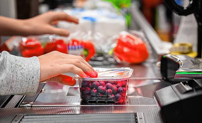 Eine Kassiererin scannt Heidelbeeren an der Kasse eines Supermarktes. Der Einkauf verrät viel über die persönlichen Hintergründe.