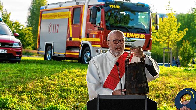 Diakon Radigk hat sich für die standesgemäße Segnung der neuen Fahrzeuge extra einen historischen Löschsack besorgt.