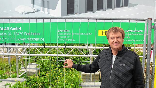 Roland Müller steht am Bauzaun, hinter diesem entsteht im Reichenauer Gewerbegebiet Göldern ein neues Firmengebäude. 1,8 Millionen Euro ...