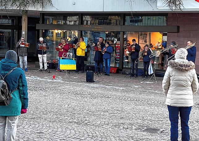Etwa 30 Zuhörer bleiben stehen und lauschen den Musikern.