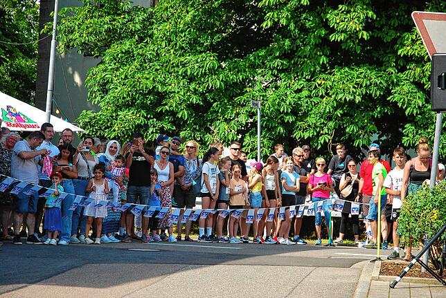 Zahlreiche Beobachter säumen den Straßenrand und warten gespannt auf die eintreffenden Sportler.