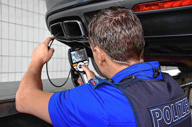 Ein Experte der Kantonspolizei St. Gallen kontrolliert den Auspuff eines Poser-Autos.