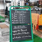 Die Tafel mit den Hinweisen auf die Spezialitäten der einzelnen Wochentage vor dem Geschäft.