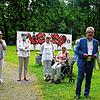 Kunstvereinsvorsitzender Frank van Veen, umringt von Gästen bei der Vernissage im Park der Villa Berberich vor der Graffitiwand.