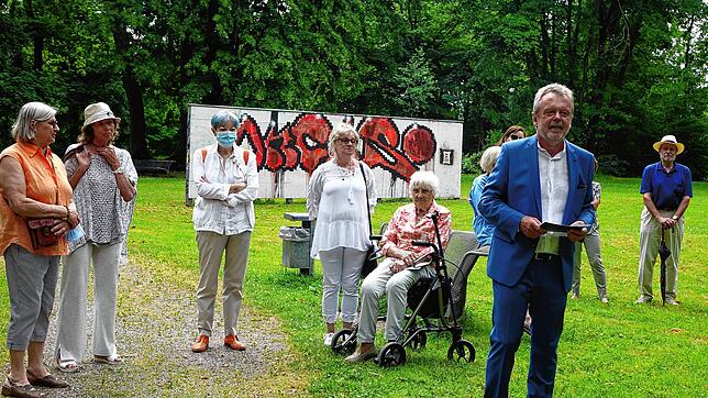 Kunstvereinsvorsitzender Frank van Veen, umringt von Gästen bei der Vernissage im Park der Villa Berberich vor der Graffitiwand.