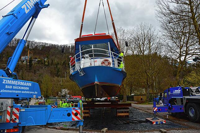 Zwei Kranfahrzeuge heben das Schiff auf die dafür vorgesehene Vorrichtung.
