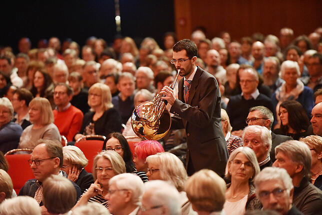 Überraschung inmitten des Publikums: Musiker der Stadtkapelle springen zu Beginn der Veranstaltung plötzlich hervor und beginnen zu spielen.