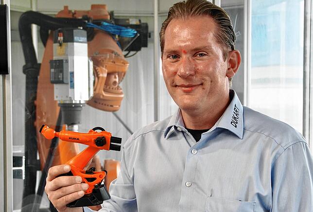 Thorsten Scholz in der Montagehalle des Maschinenbauers mit einem Mini-Roboter.