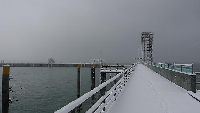 Eine dicke Schneeschicht hat sich in der Nacht auch über Friedrichshafen gelegt. Zum Moleturm führen am Morgen erst wenige Spuren.