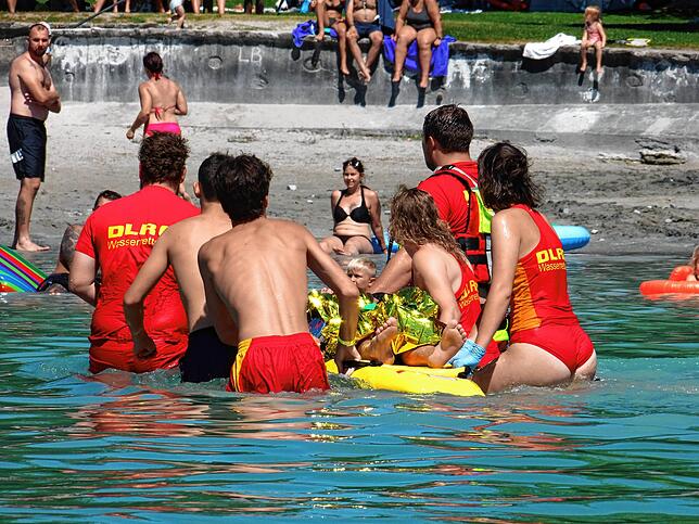 Rückenschonend auf einem Spineboard und mit einer schwimmenden Trage transportieren DLRG-Rettungskräfte den verletzten Wassersportler an ...