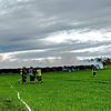 Einsatzkräfte mit Atemschutzmasken löschen am Sonntag, 20. April, die brennenden Strohballen.