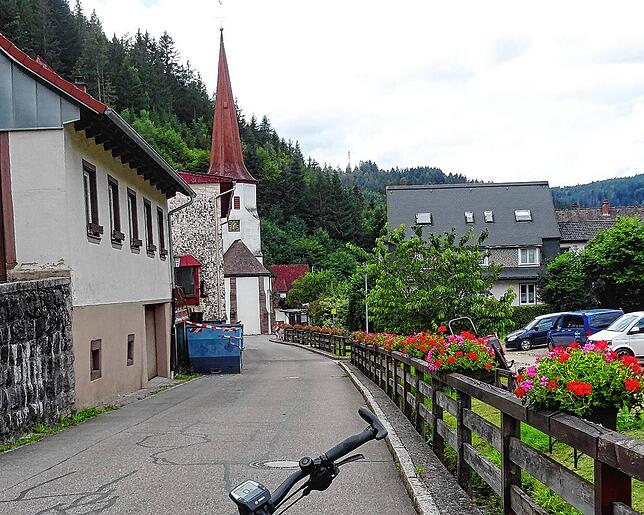 Blühende Geranien und der Kirchturm grüßen den Radler: Nach rasanter Abfahrt in Nussbach angelangt.
