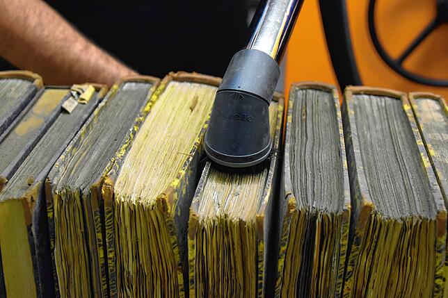 Der Unterschied ist deutlich: Auf den Büchern liegt viel Staub aus Jahrzehnten oder sogar Jahrhunderten. Das Gröbste landet vor dem ...