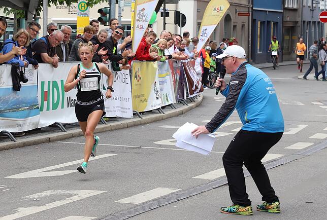Moderator Michael Fleiner feuert Samira Schnüriger vom LC Regensburg an, die Siegerin im Zehn-Kilometer-Lauf wurde.