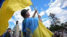 Ein Mann schwenkt in Berlin die ukrainische Flagge. Bislang können ukrainische Wehrpflichtige in Deutschland Bürgergeld erhalten.