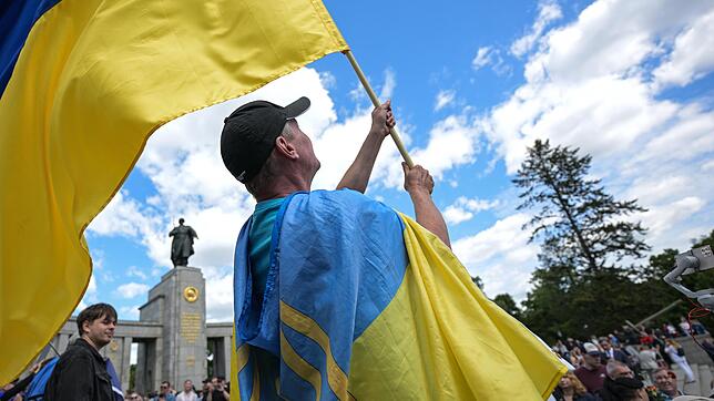 Ein Mann schwenkt in Berlin die ukrainische Flagge. Bislang können ukrainische Wehrpflichtige in Deutschland Bürgergeld erhalten.